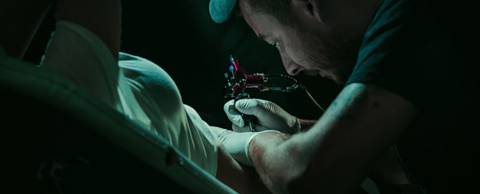 Tattoo artist tattooing a male customer.