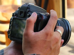 Tattooed hands holding a professional camera.
