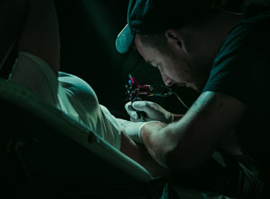 Tattoo artist tattooing a customer.