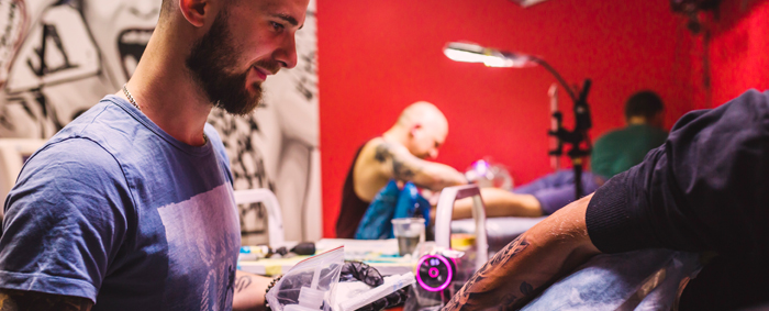 Male artist working on arm tattoo in a tattoo shop
