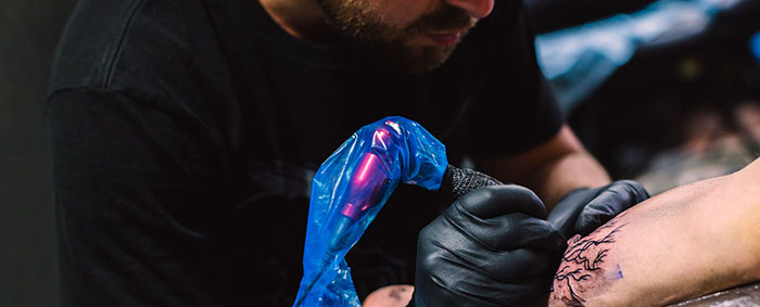 Male tattoo artist tattooing a customer