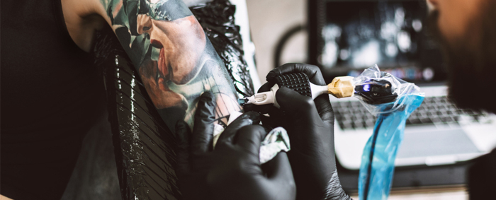 Tätowierer arbeitet an einem von Catwomen inspirierten Tattoosleeve