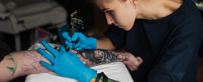 Ein weiblicher Tätowierer arbeitet an einem Tattoosleeve