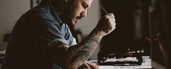 Un homme tatoué dessinant dans un carnet de croquis