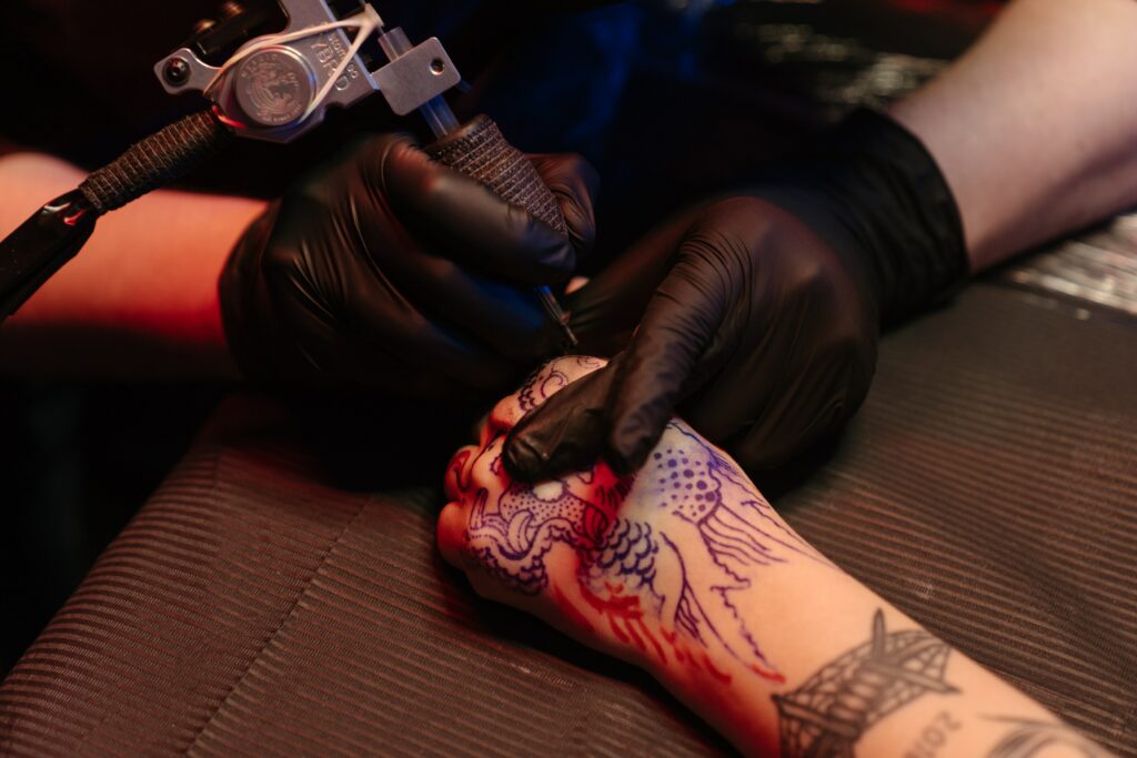 Hand getting tattooed with a coil machine.